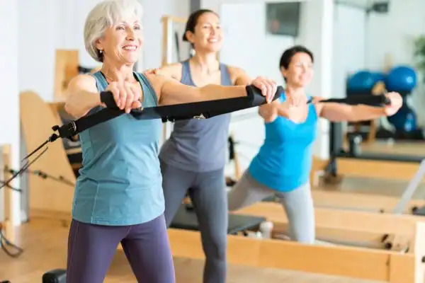 Toning Arms After 60: Empowering Womens Fitness Through Effective Weight Training 2 older woman doing weight training Bridgend and resistance in the gym to tone upper arms