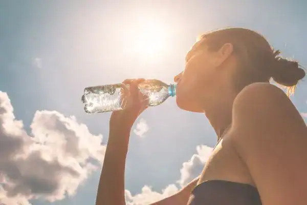 Hydration: The Secret Ingredient for a Toned Stomach and Enhanced Fitness 3 Image of woman drinking water to hydrate Bridgend after run.
