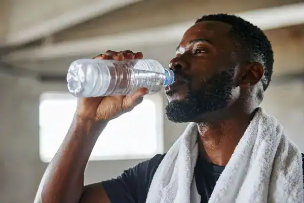 Image of man drinking water to improve hydration Bridgend after work out.